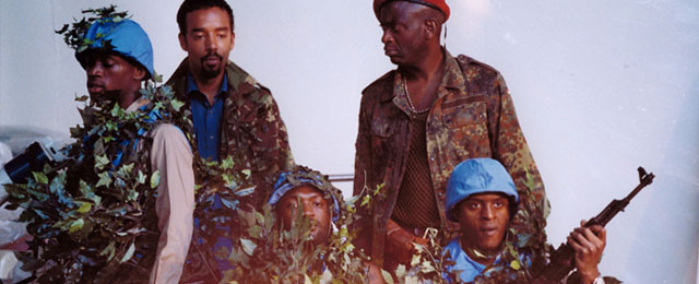 Men dressed in blue United Nations military helmets and camouflage jackets, holding guns
