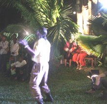 A man performing at night in a garden with tropical plants