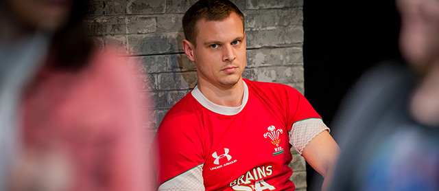 a man is looking ahead with a stern look on his face wearing a red rugby shirt