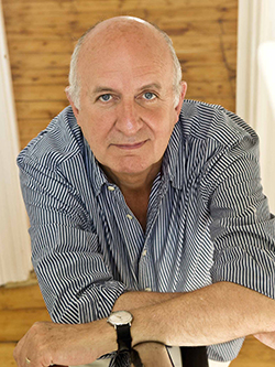 a middle aged man smiling and leaning on a banister